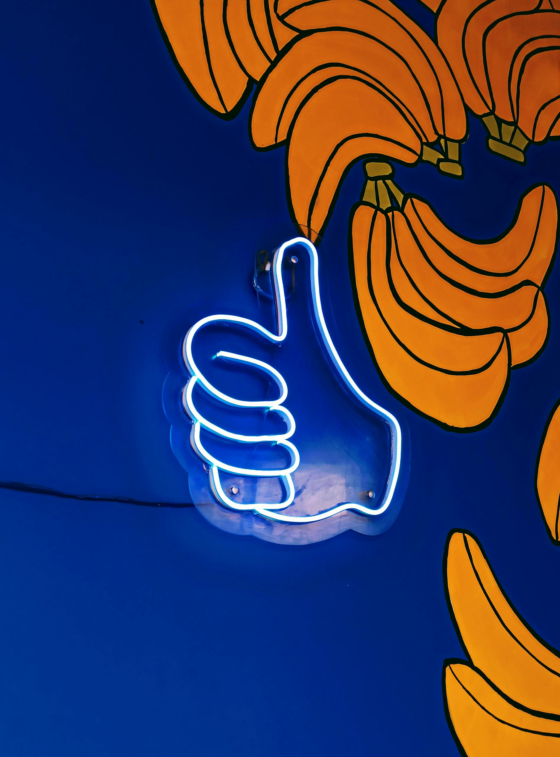 Neon thumbs-up sign on a colorful painted banana wall in Karaganda, Kazakhstan.